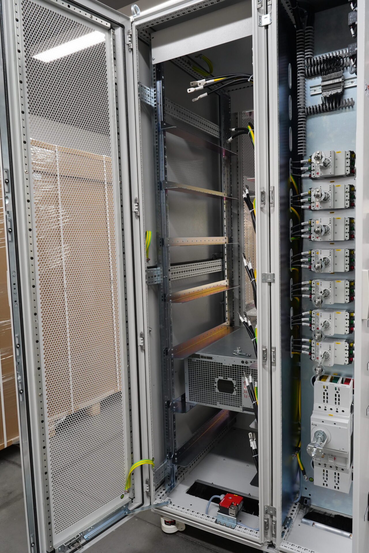 Innenansicht des 48U Power Cabinet mit mehrstufiger DC-Sammelschienen-Infrastruktur, Hochstrom-Kupferschienen, Temperatursensoren und parallelen Leistungsmoduleinschüben. Demonstriert das thermische Engineering-Design mit 85 Prozent offener Perforation der Seitenwände